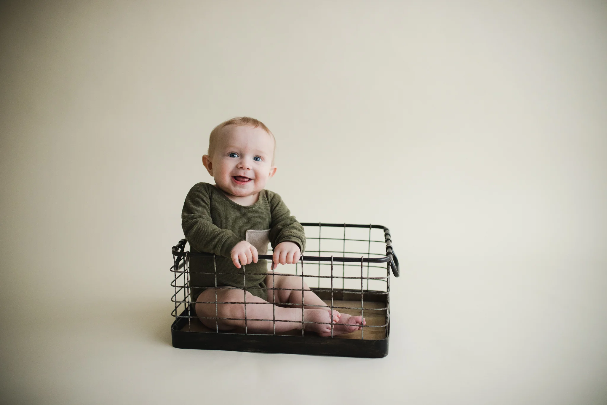 Six month old boy sitting and smiling during a milestone photo session with Laura Anne Photography in Cedar Rapids, Iowa.