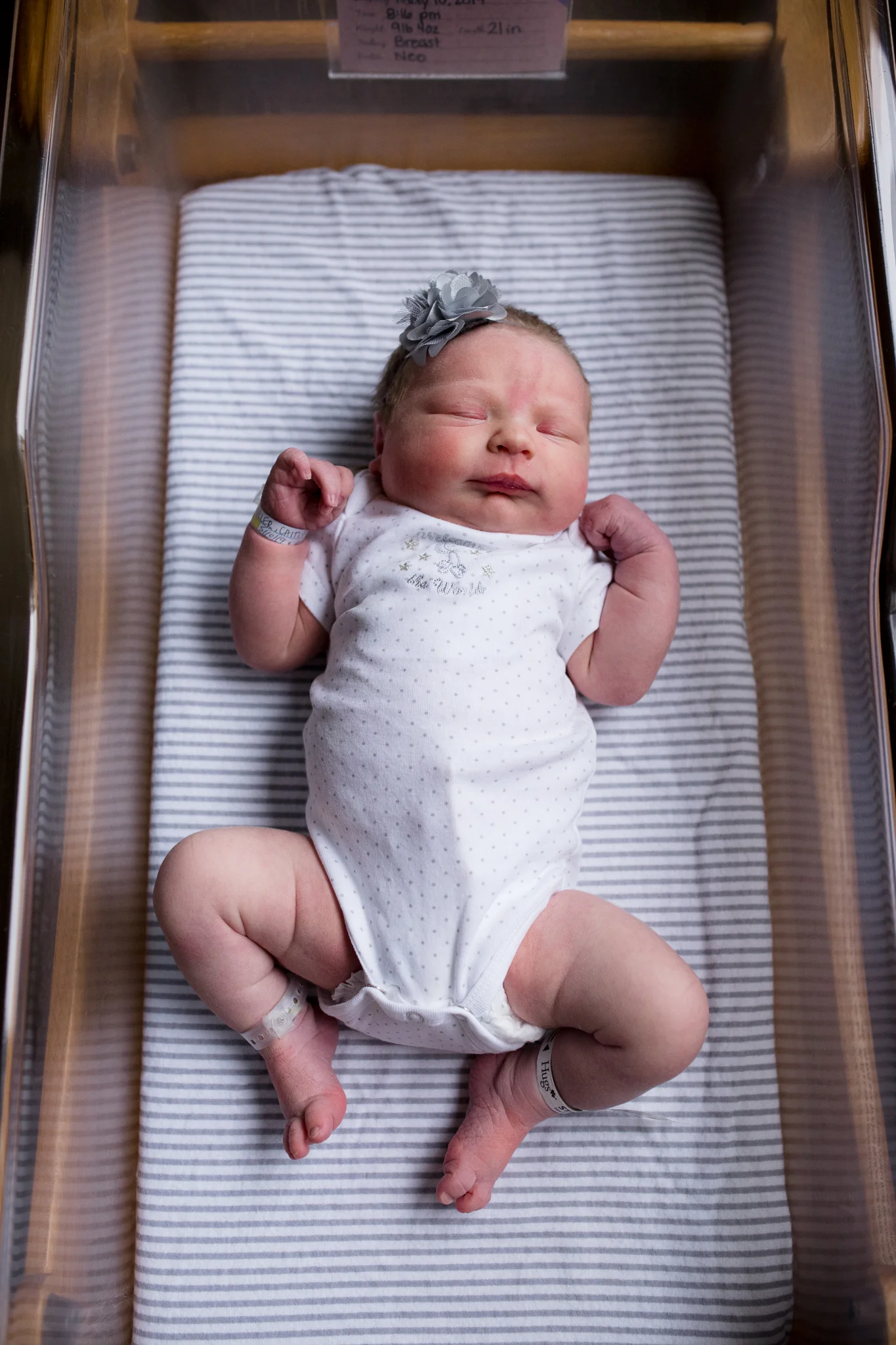Newborn baby girl laying in bassinet at hospital during Fresh 48 photo session in Cedar Rapids, Iowa.