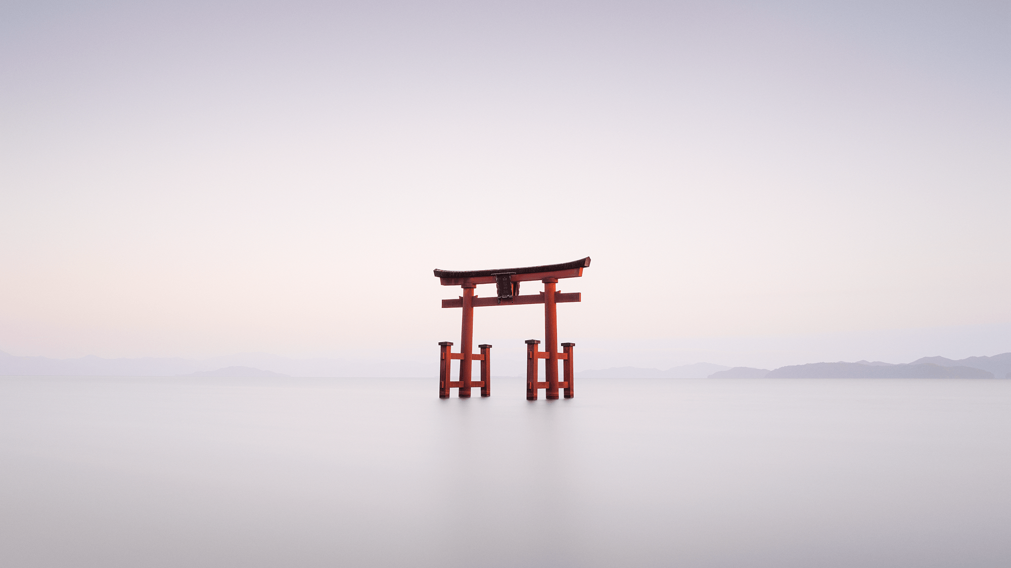 Minimal long exposure scene with red torii gate in still water