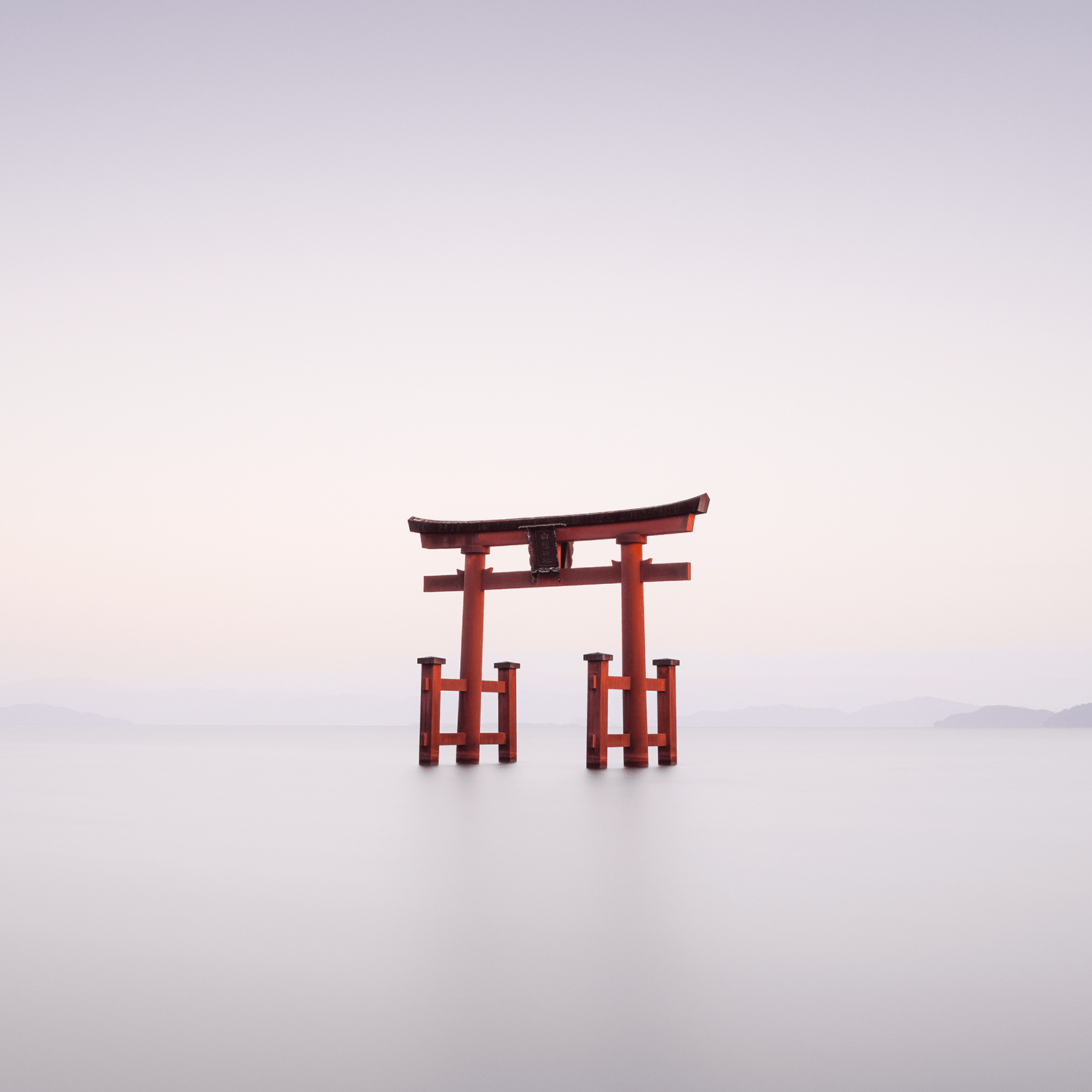 Minimal long exposure scene with red torii gate in still water