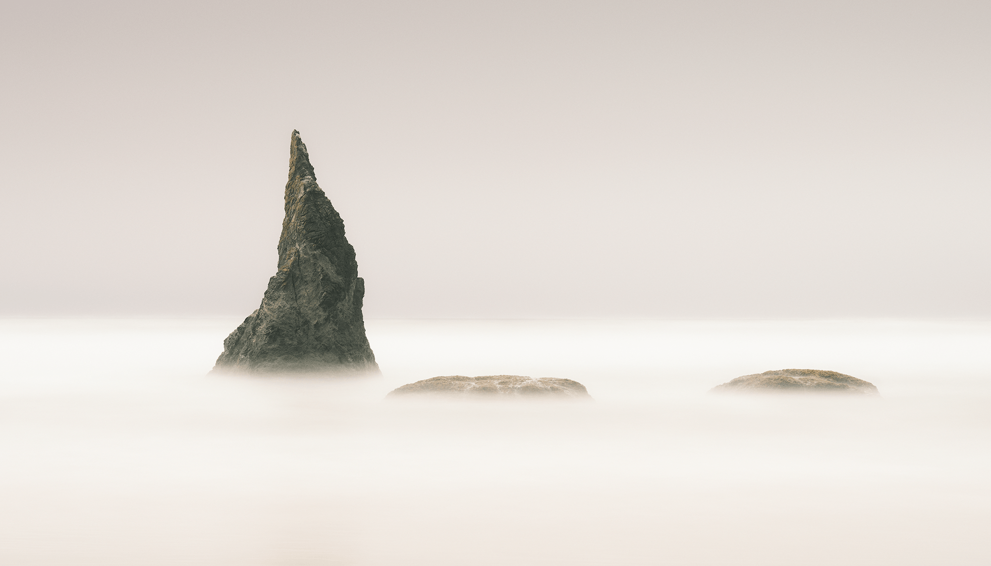 Pointed sea stacks poking up out of smooth waters.