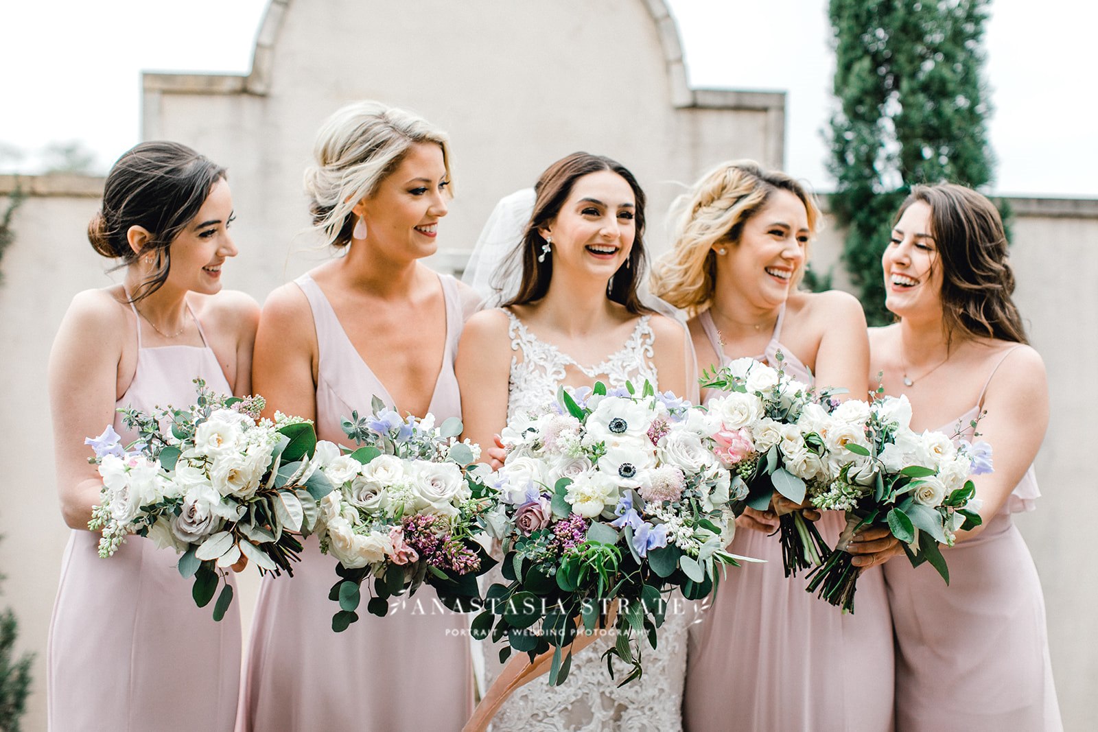  bride and the bridesmaids holding their white wedding bouquets 