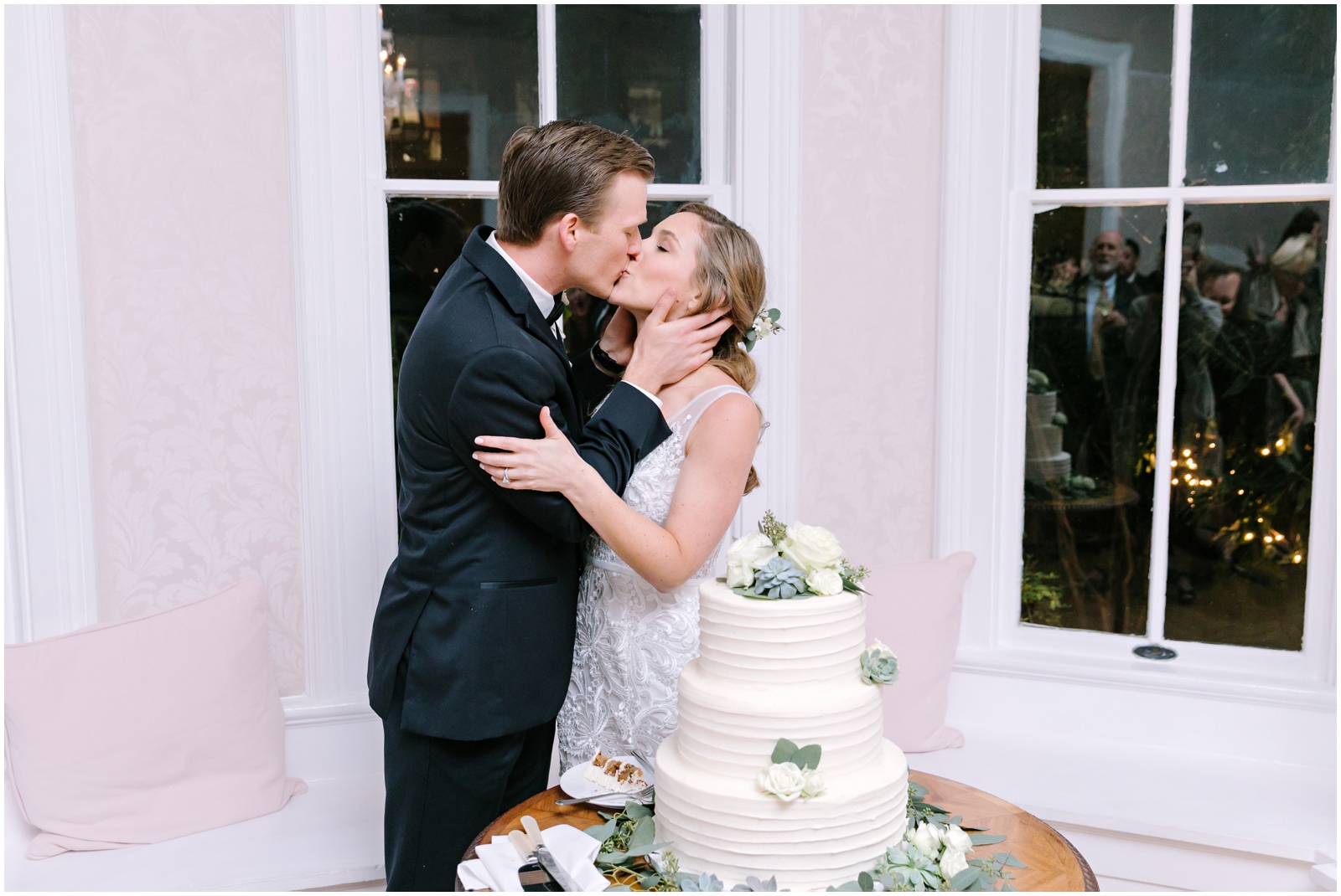 Bride and groom kiss before cutting their wedding cake