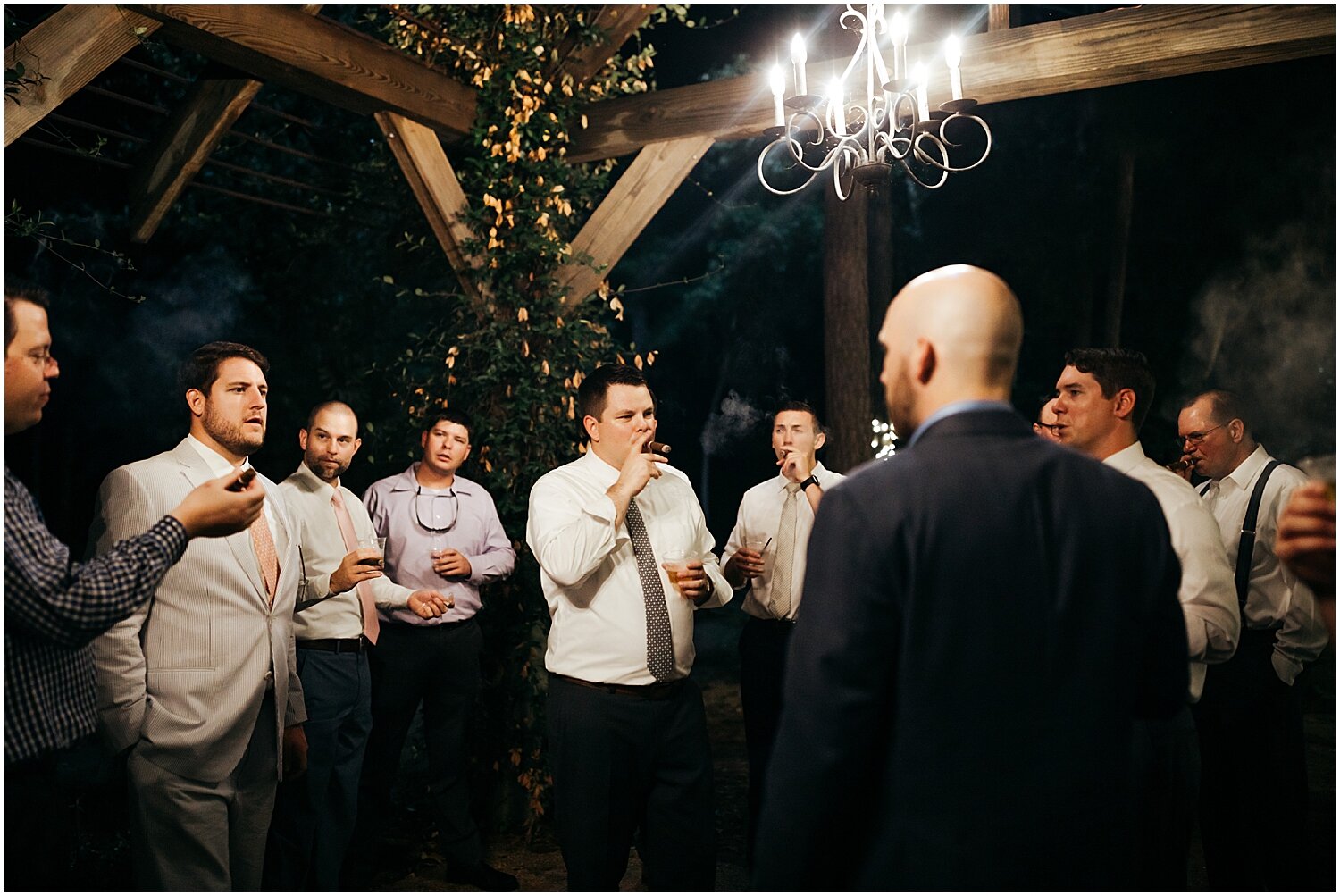  groom and wedding guests smoking cigars at wedding reception 