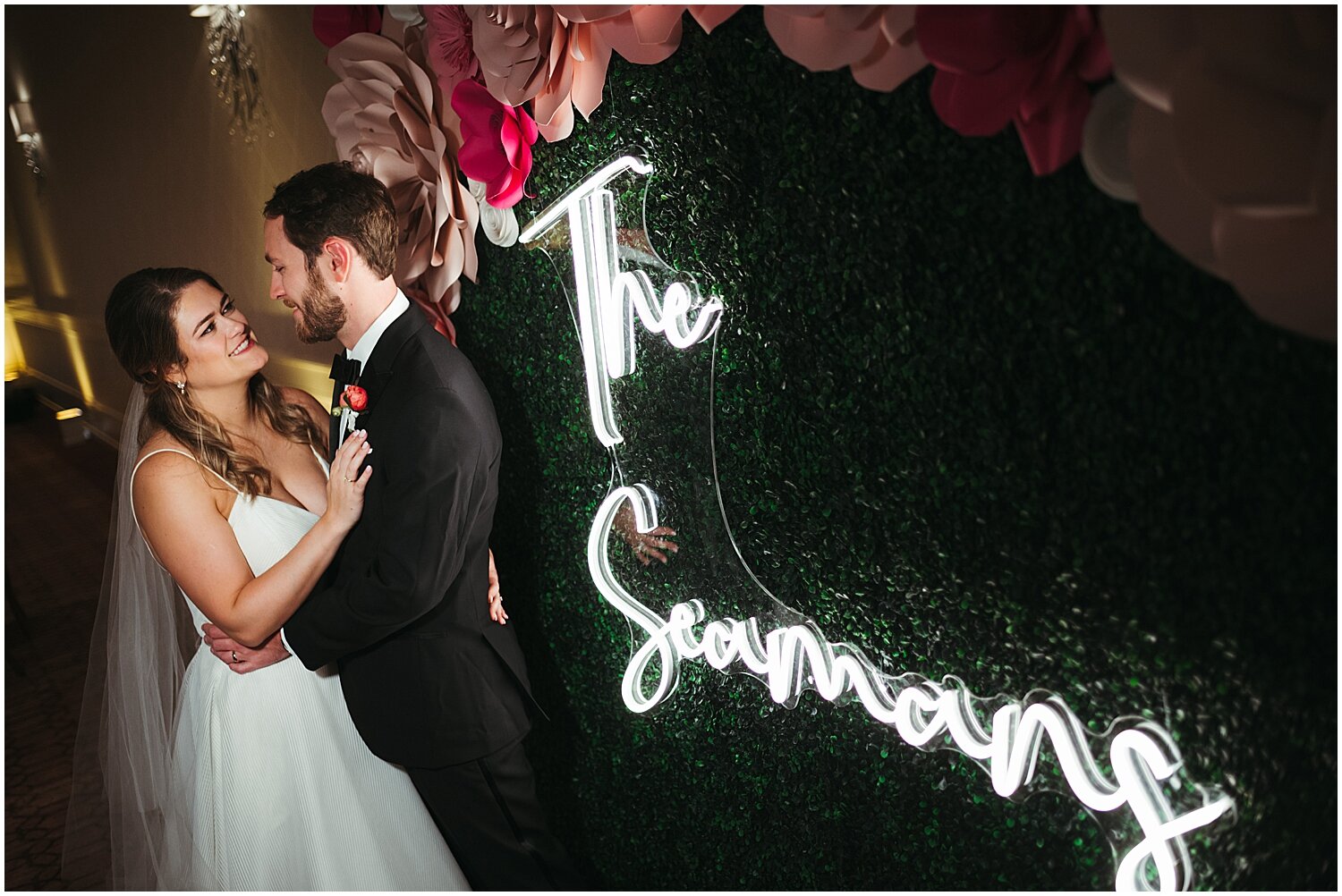  bride and groom portrait by the neon sign and greenery backdrop 