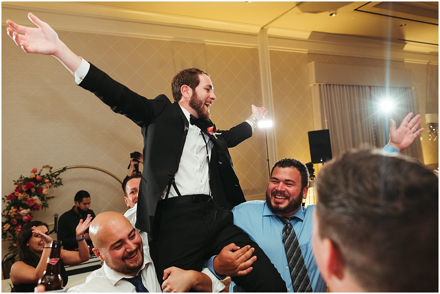  wedding guests carrying groom during their reception 