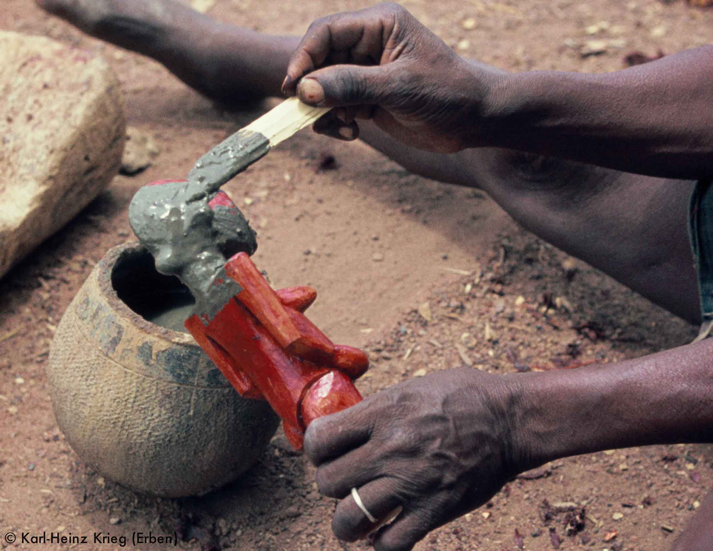 Songuifolo Silué colouring a wooden figure with a red plant-based paint and iron-rich river mud. Photo: Karl-Heinz Krieg, Sirasso (Boundiali region, Ivory Coast), 1978