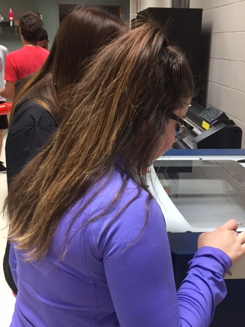 Graphic Design watches as her project is completed with a laser printer.