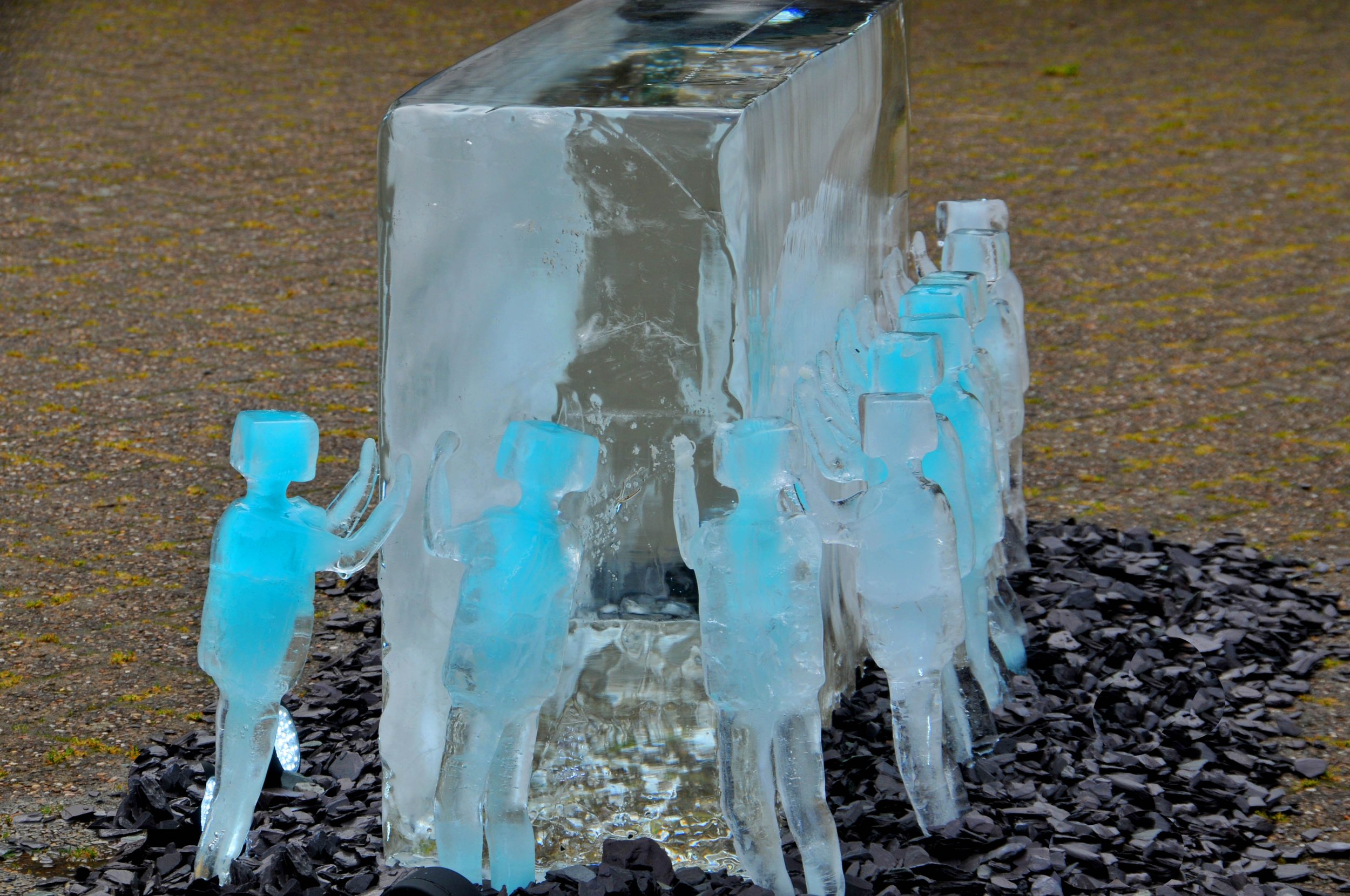 Ice sculptures of human figures surrounding a large ice block.
