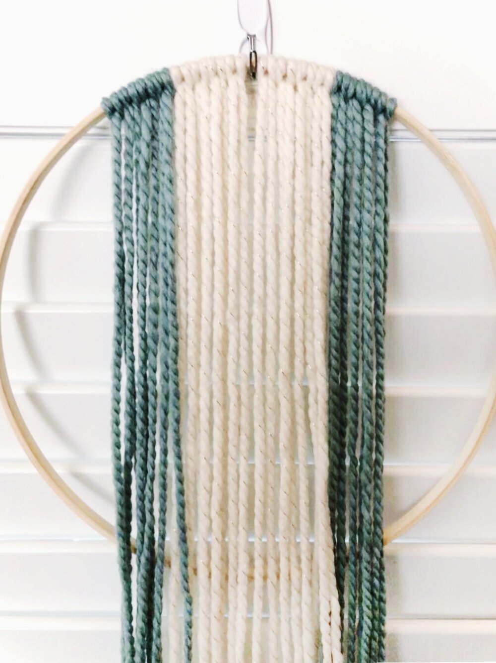  Determine the length you would like your fringe to be. Hold a folded piece of yarn at the top of the hoop and let it hang down to your desired length. Using the first strand as a guide, cut 16 strands total. Attach all strands with a Lark’s Head kno