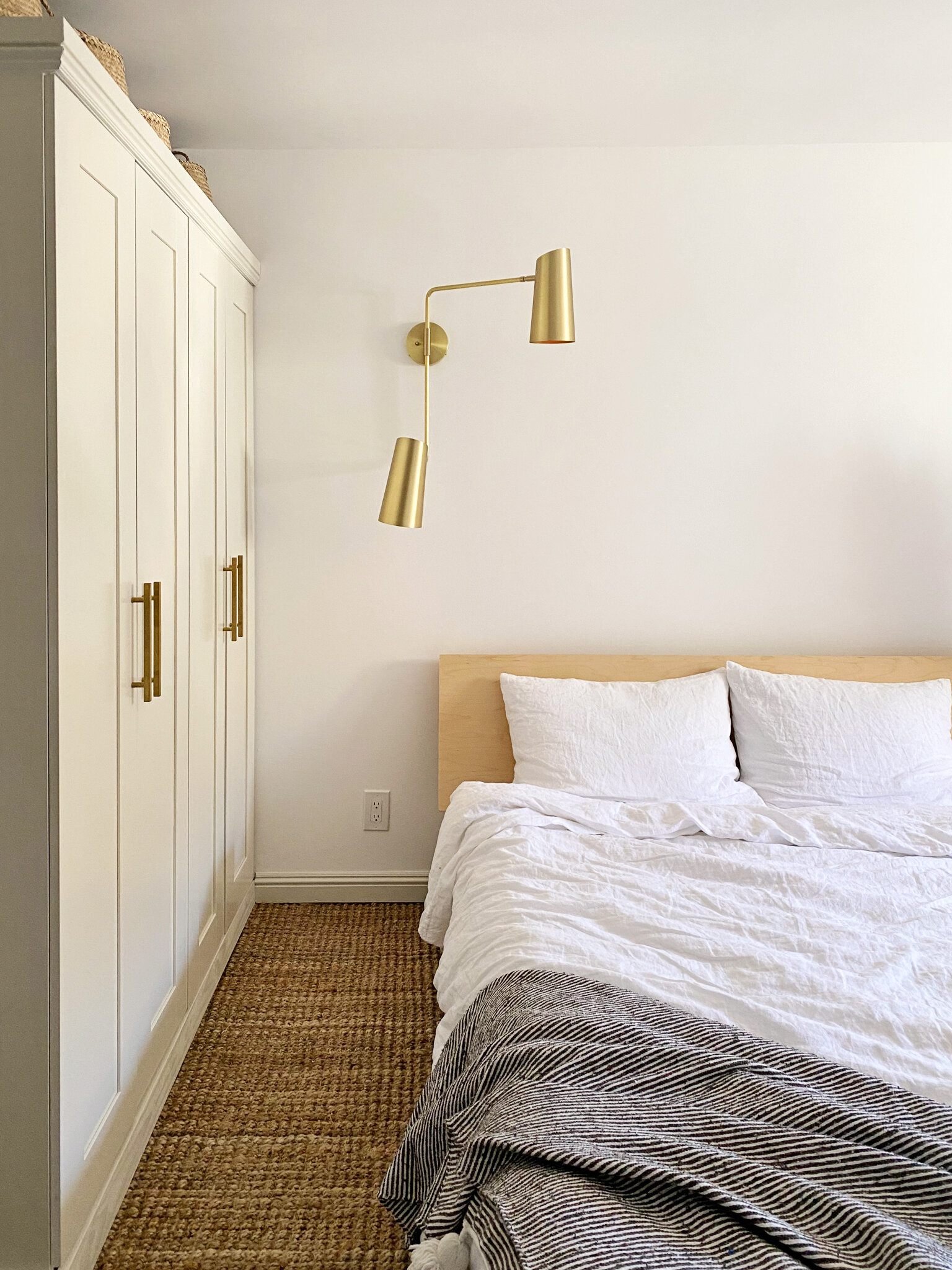  Instead of centering the bed on the wall between the sconces, we paired it with a light that could be extended over the bed and grouped the pair with the wardrobe to carve out a zone. 