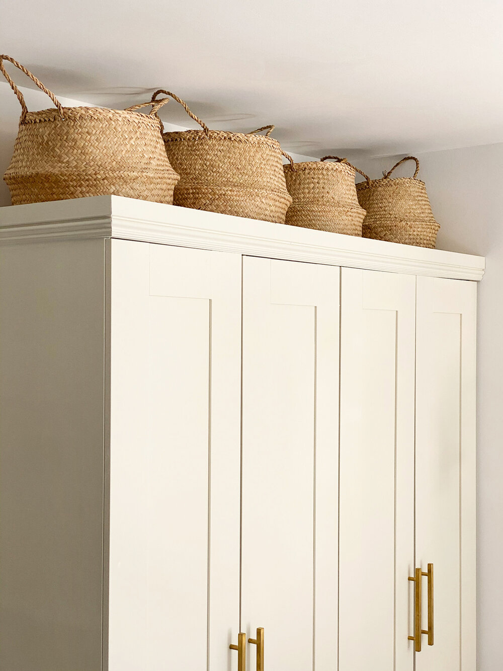  Topping the wardrobes with a row of seagrass baskets helps utilize every square inch of the wall for storage. 