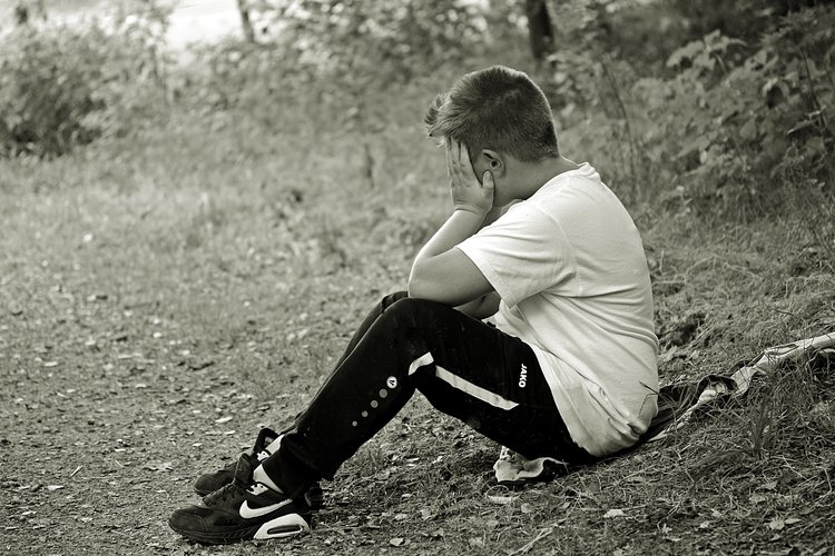 boy-profile-hiding-face-sitting-knees-bent-black-white.jpg