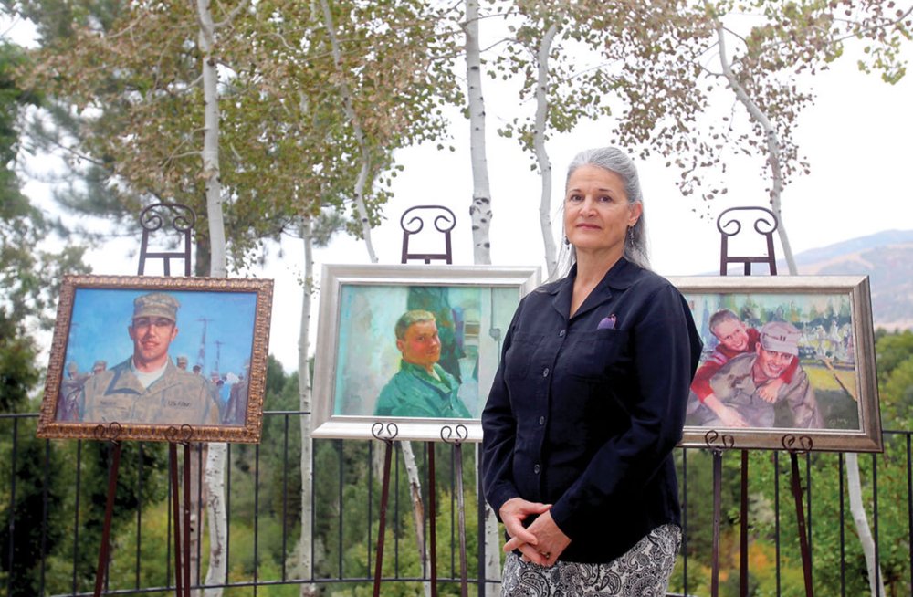 Anne Marie Oborn with some of the 250 portraits she has painted for the families of fallen members of the military. (Photo courtesy of the Standard Examiner)