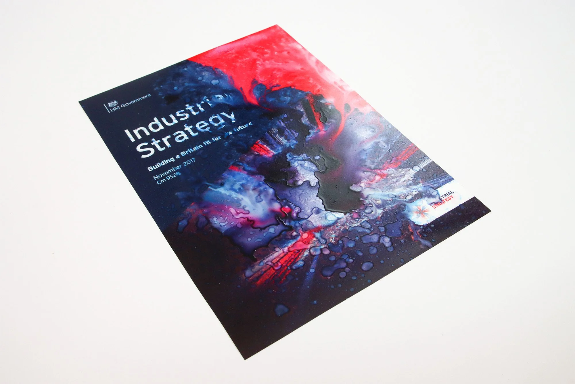 Altered Industrial Strategy government report cover in dark blue, red and pale blue, with printed imagery disrupted and pooled by water.