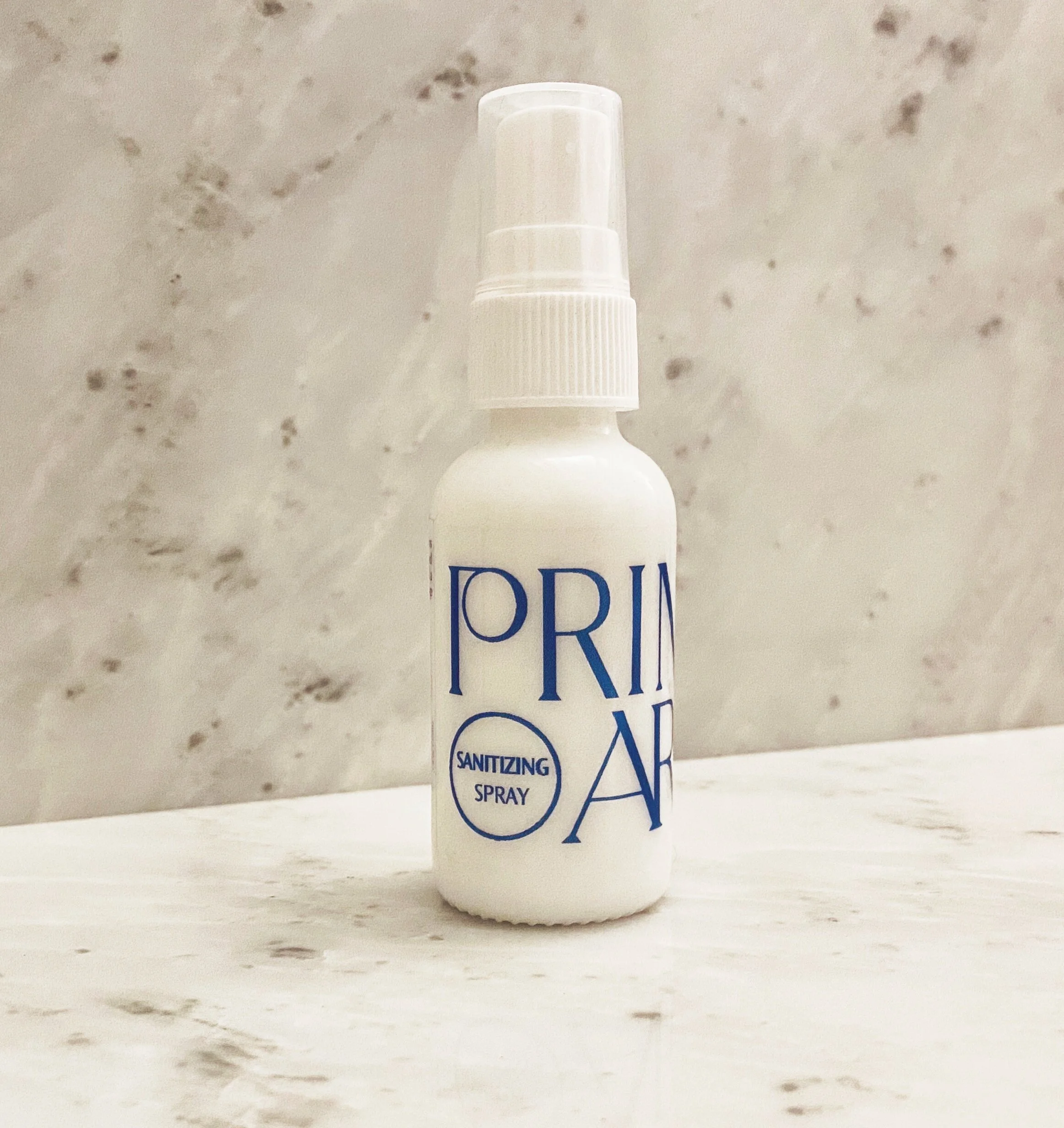1 oz white glass bottle with blue hand sanitizer logo on marble background