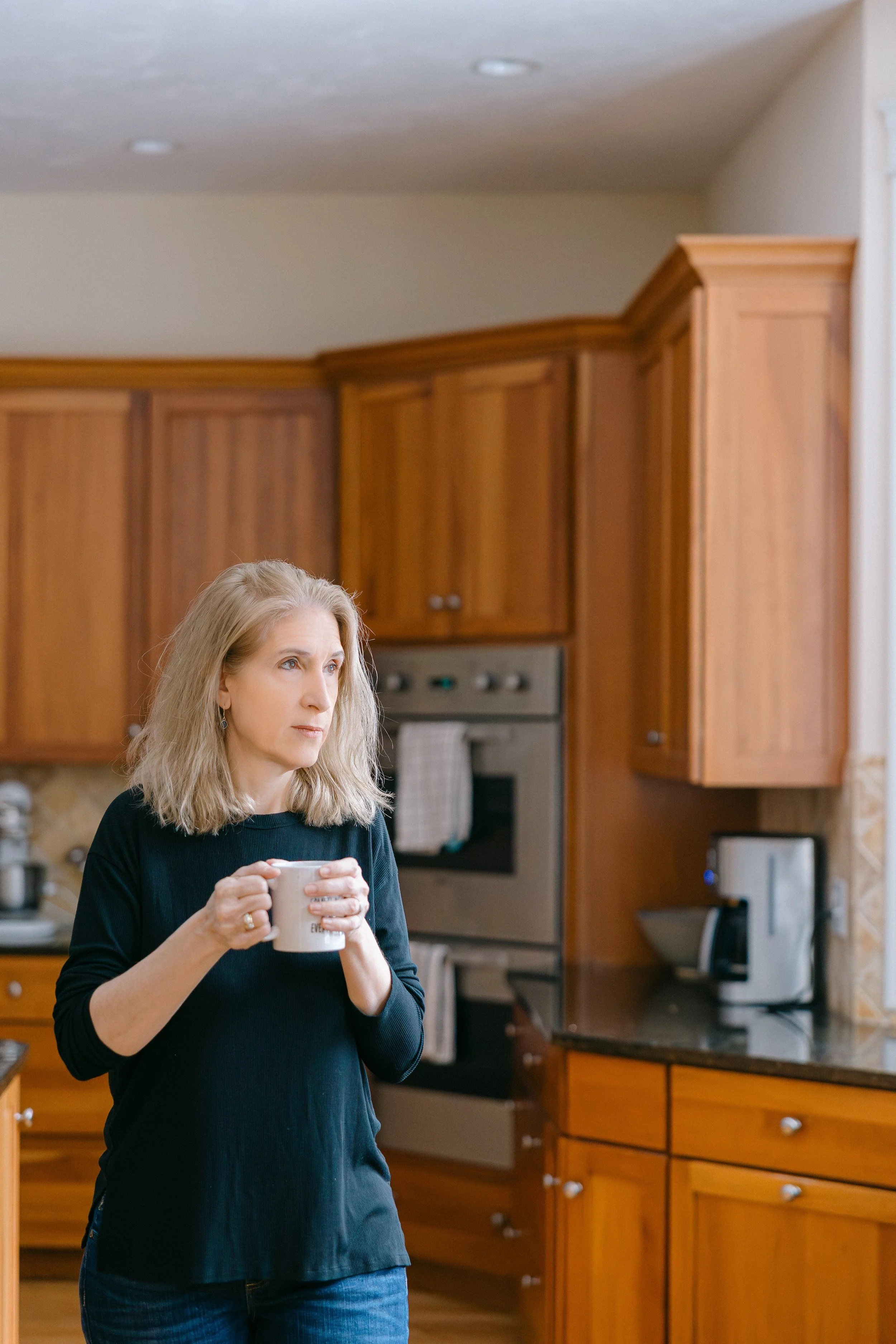 Catherine stands in her kitchen with a mug