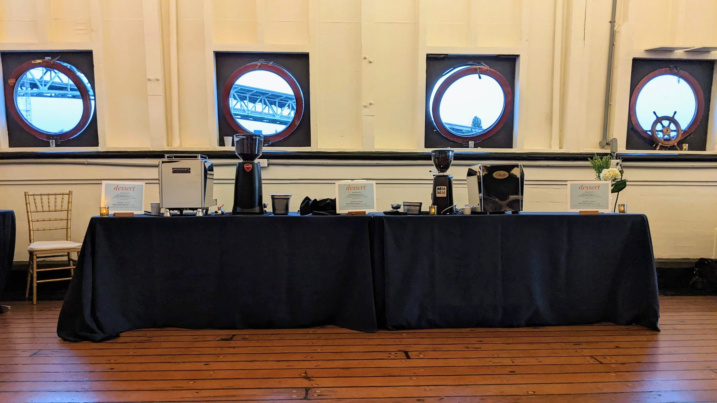Elegant espresso bar with dessert menu signs set up at a waterfront wedding venue with porthole windows in Seattle