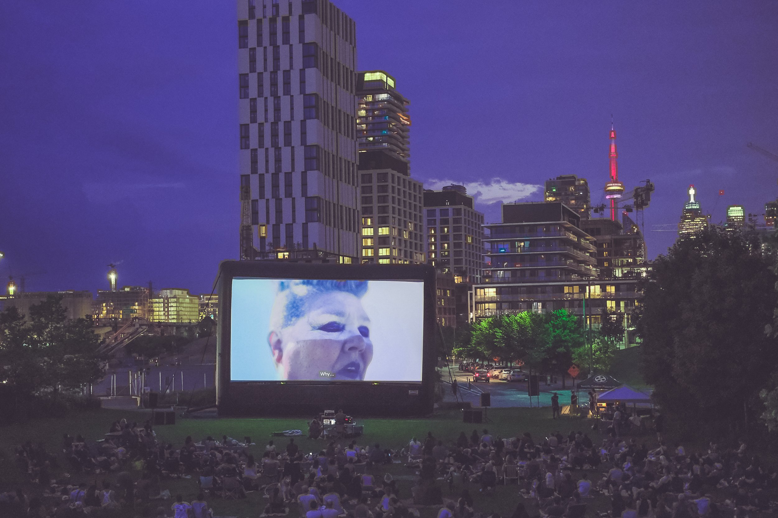  Canadian short film “Monologue Harmonic” is onscreen, with CN Tower and city skyline lit up behind the movie screen 