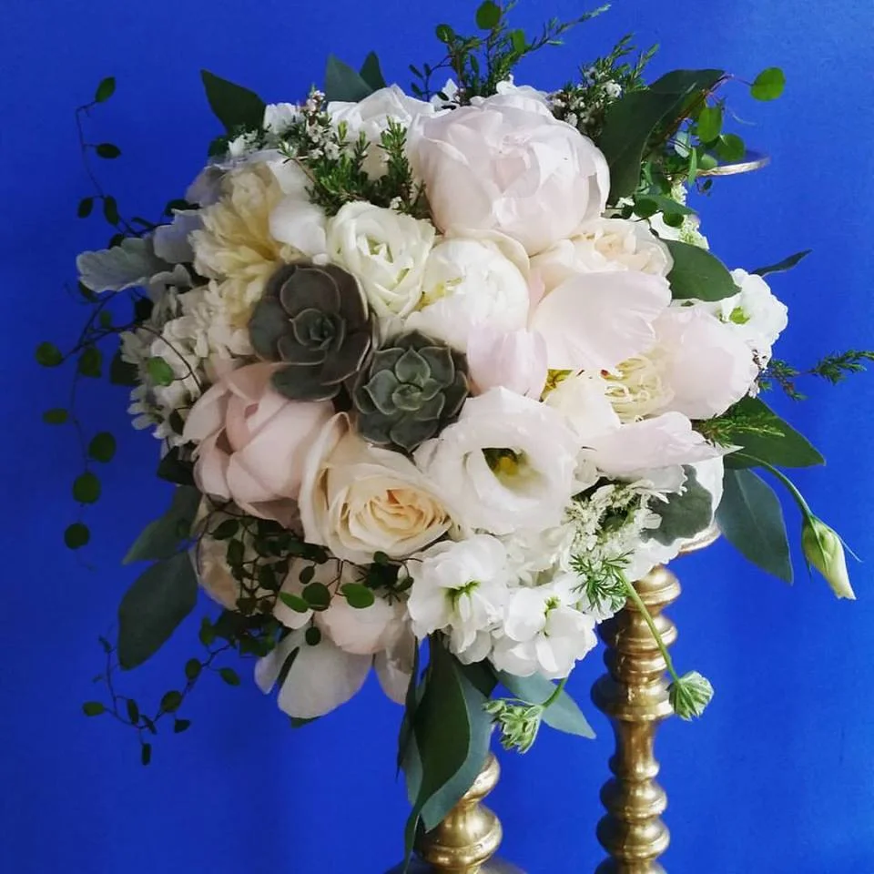 Loose and Natural Bouquet Light and airy pink peonies, aromatic stock, and white ranunculus are studded with white lisianthus, and garden roses. Natural petite succulents and angel hair vines complete the look. 