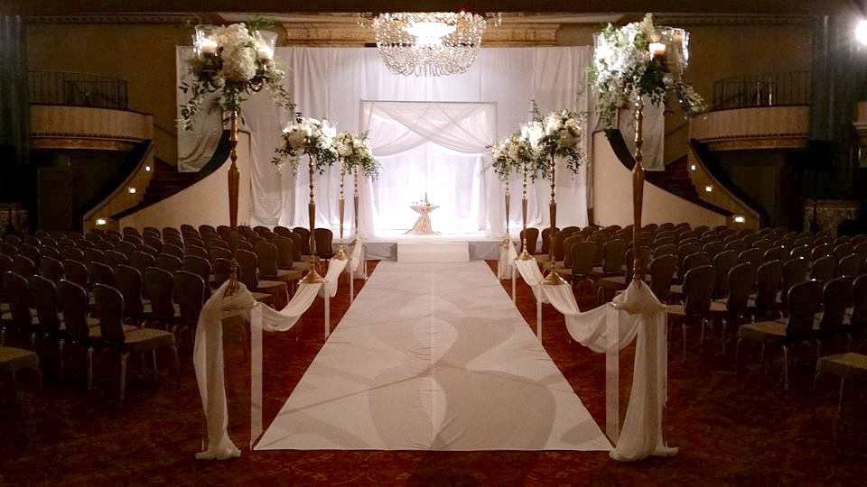Elevated & Traditional Chuppah Dramatic "statement pieces" placed down the aisle. Classic white chiffon chuppah at the end of the aisle, with fabric panels pulled to the frame creating a "criss crossed" design, puddling to the floor.