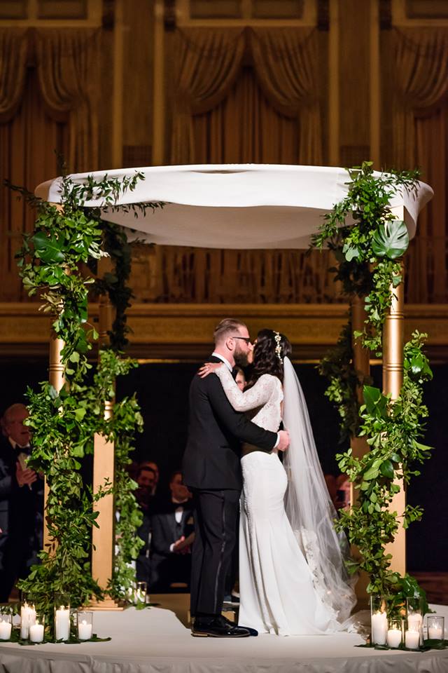 Structural Chuppah with Greenery Metallic Posts crawling with ivy garland and grounded with a romantic candle treatment create a natural setting in the most traditional and ornate spaces. Photo Credit: Kent Drake Photography Venue: Palmer House Hilton