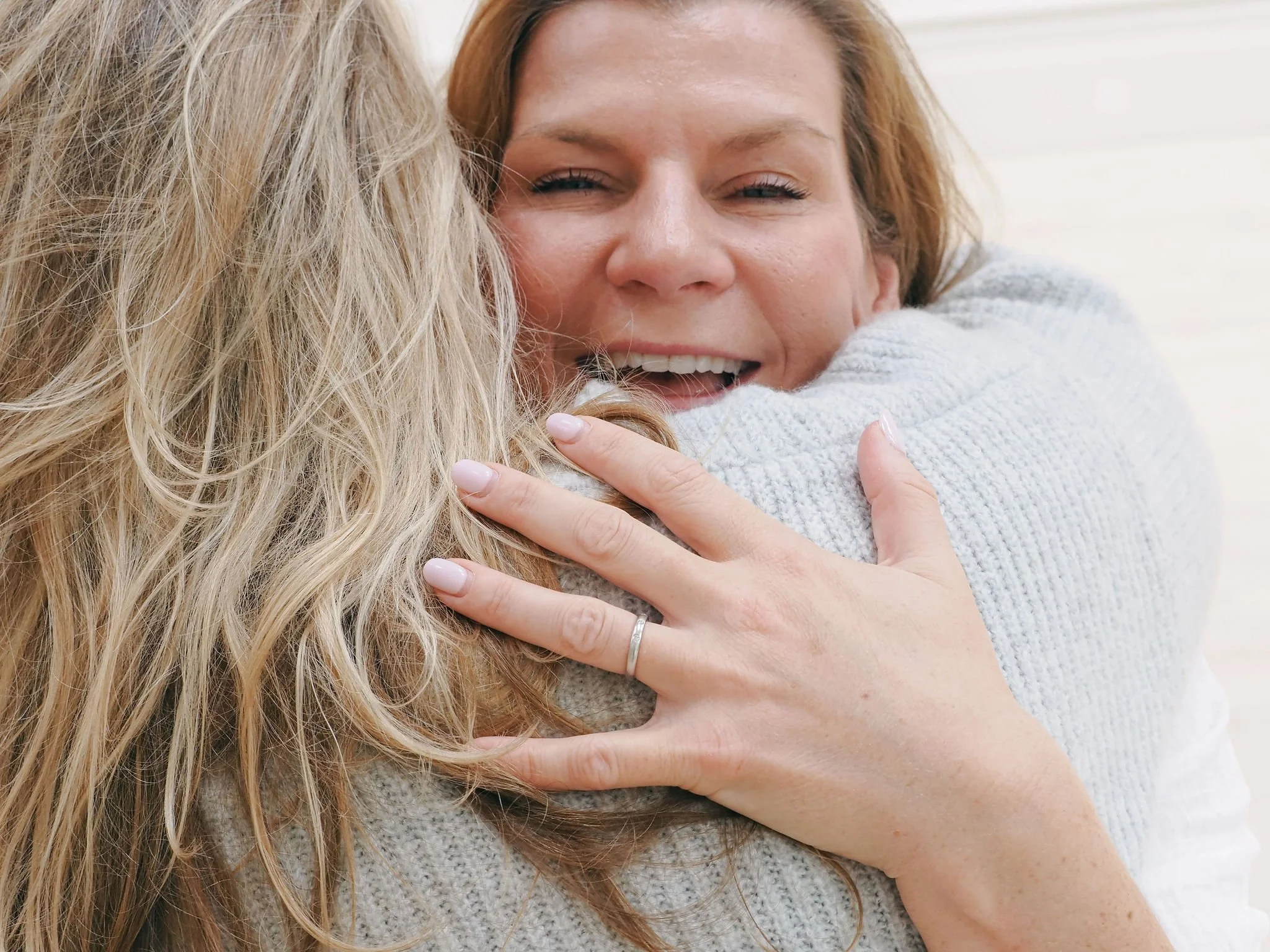 Two women hugging, one with blonde hair and one with red hair, smiling and showing affection.