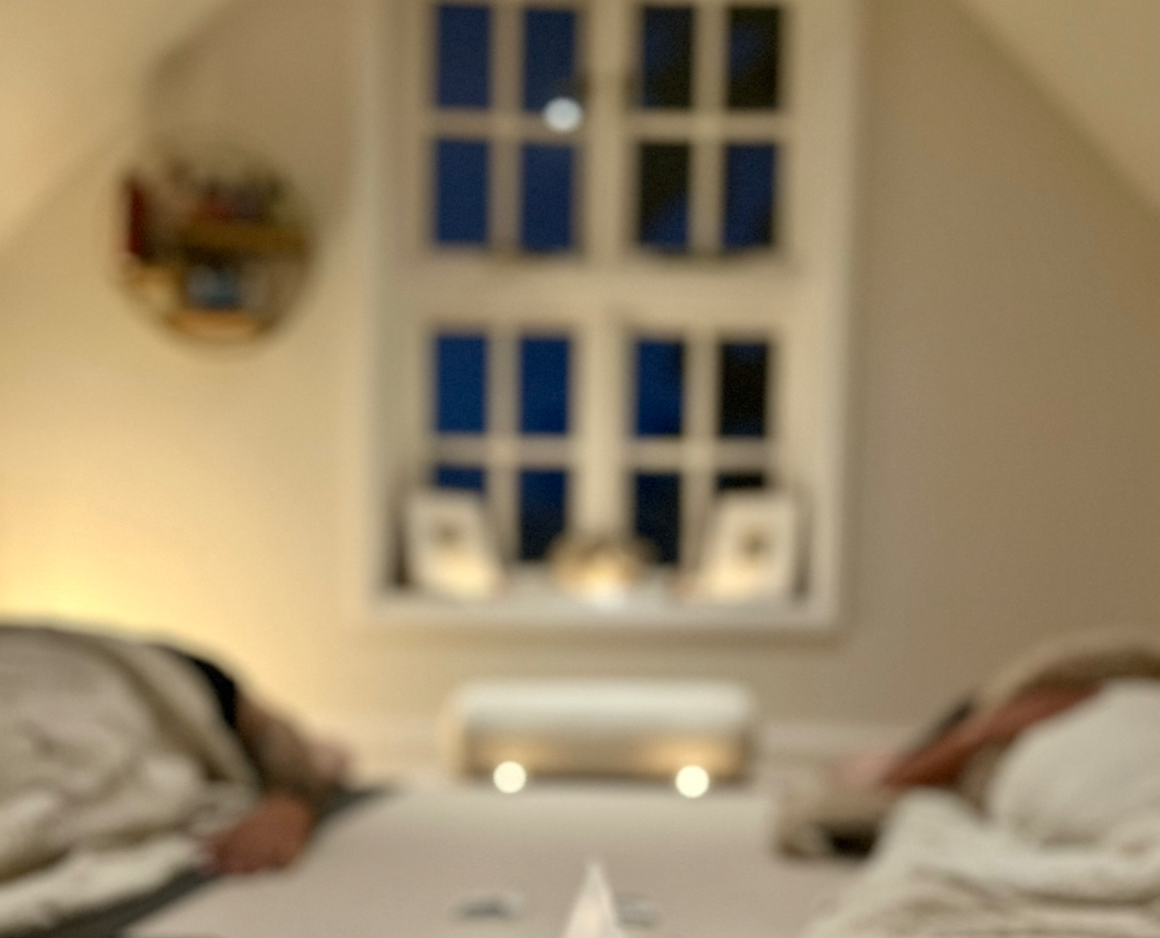 A blurry photo taken from a person's perspective looking down at their feet, showing sneakers, with a staircase and a door in the background.
