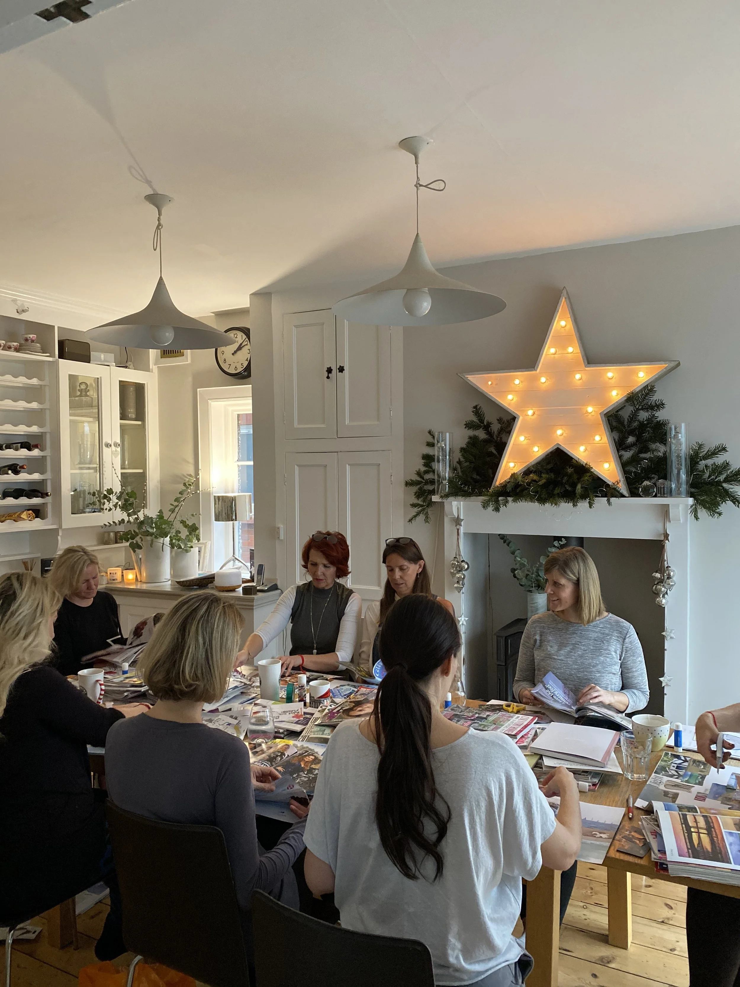 Women gathered around the table during In Between the Years, sharing conversation, creativity and vision board making.