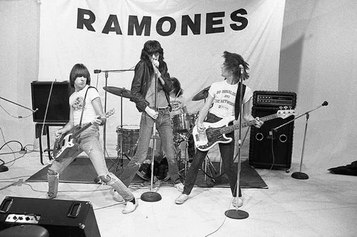 “With their first album ready to release in early 1976 the Ramones were booked into M.P.C.S’s TV studio to shoot what Rock Scene Magazine would refer to as a ‘special 20 minute full colour surprise TV show’. I was there taking pictures. Arturo Vega’s backdrop with the band’s name seems to sag a bit, but that would add to the punkiness of the production, it was hoped!” -Danny Fields