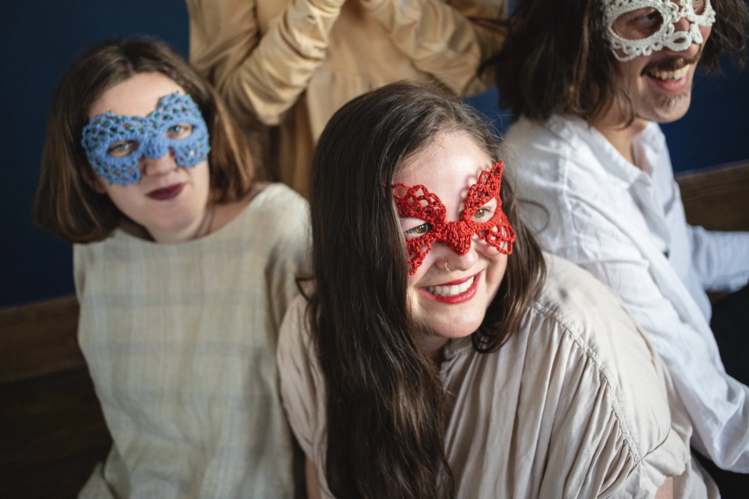 A group of four people, three of whom you can see wearing one of a kind crochet masquerade masks