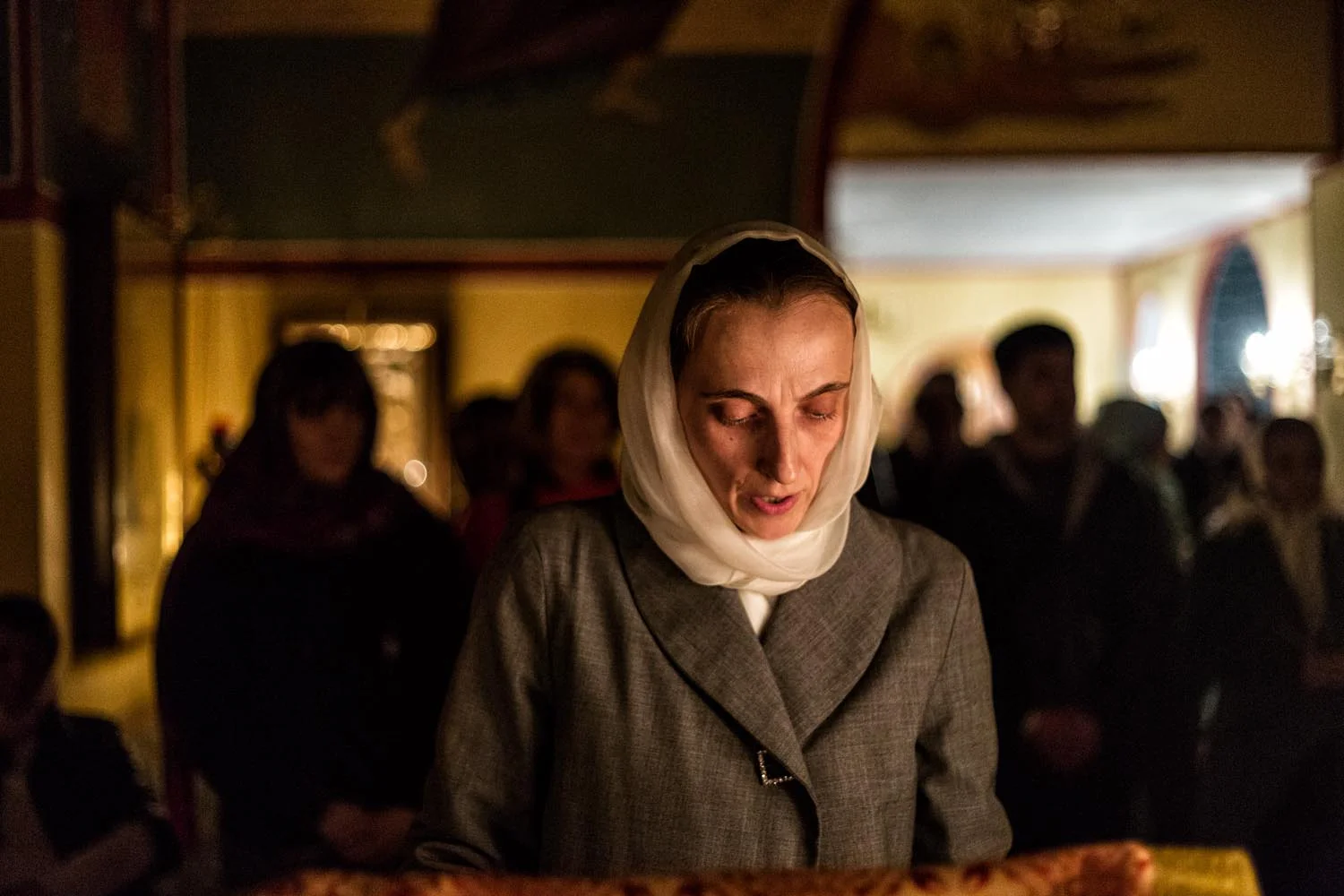 Rome, Italy, Apr 2018. Saint Chaterine Church. A russian orthodox believer, Maryia, reads the Acts of the Apostle before the divine liturgy which will start after midnight. Behind her, the other believers are praying.