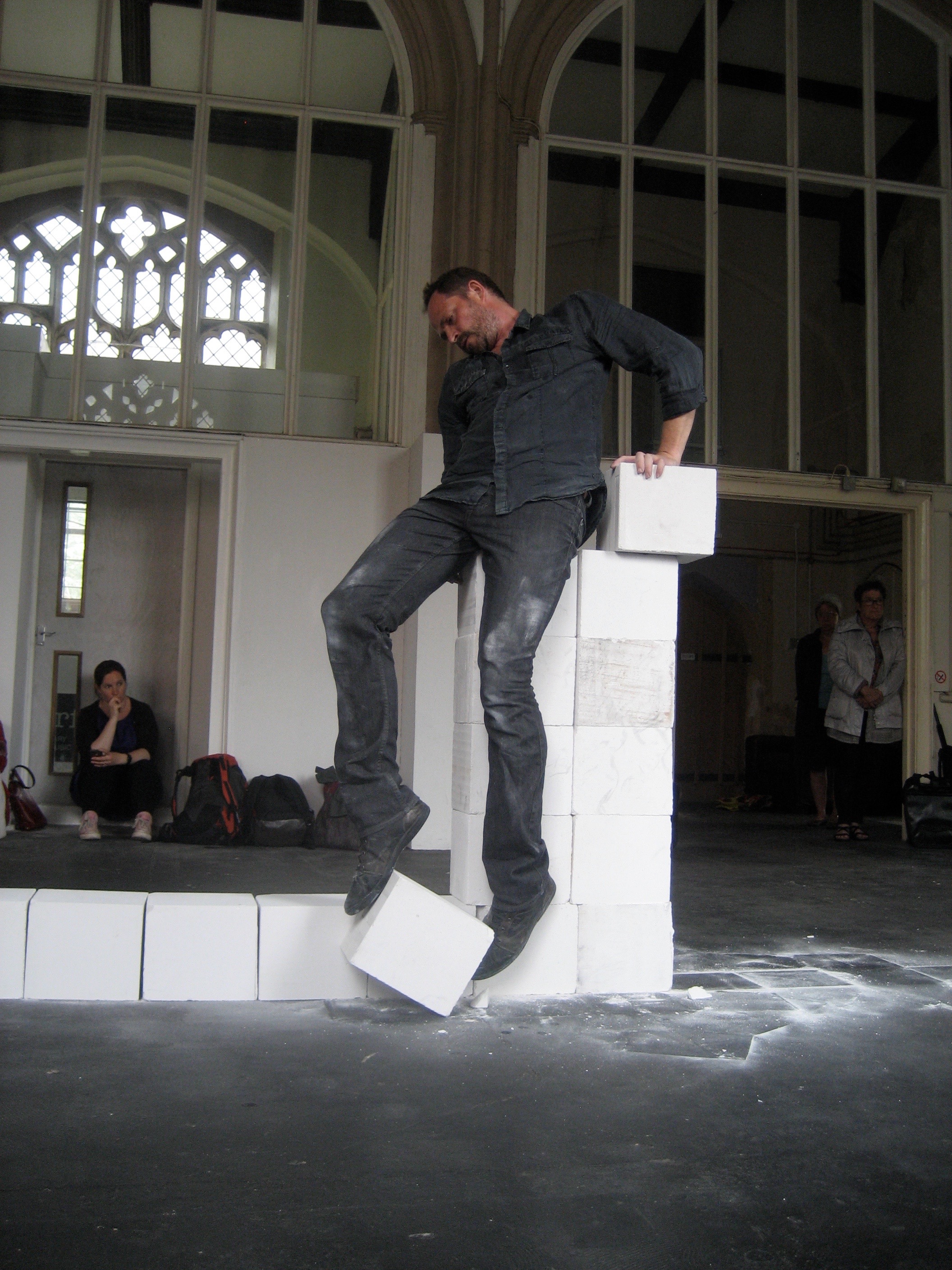 Claude Cattelain For the performance ‘Colonne empirique en ligne’, he reconstructs a horizontal line of white Ytong blocks into a vertical column, moving them one by one from their ground line. In doing so, his body must not touch the ground, so the column becomes both his task and his perch. His balance is increasingly perilous, grasping the next block becomes ever more challenging and eventually impossible. Here it is being performed in Norwich in 2014 as part of a European cross-channel ‘Interreg’ funded programme ‘Time and Place'. fabrica.org.uk