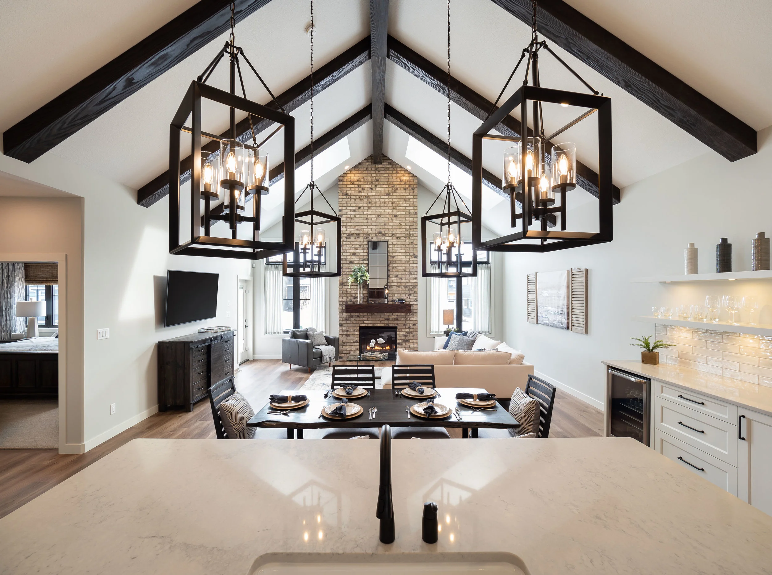 A floor to ceiling fireplace is the focus in the living room with large lantern lights in the kitchen balancing the room.