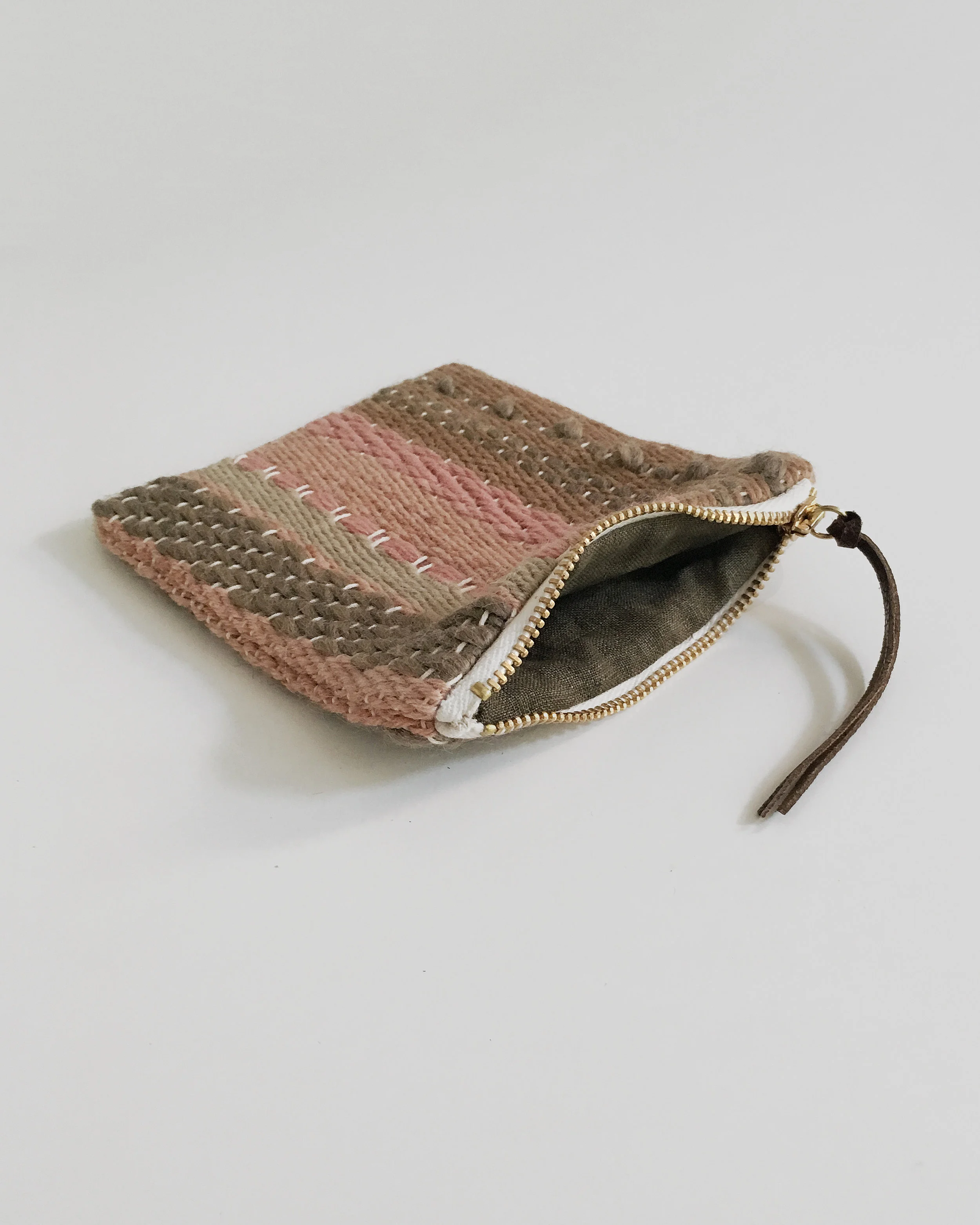 Handwoven zipper pouch made with plant dyed yarns and lined with botanically dyed linen. Unique and handmade artisanal piece.