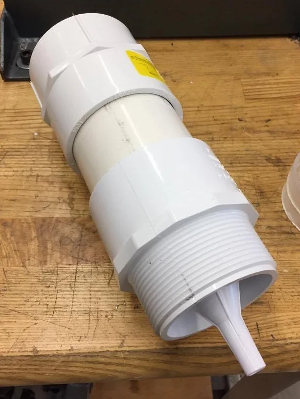 Typical filter unit with PVC body and adapters. This particular unit has the funnel at the output. Filter cartridges were fit between the PVC and adapters inside the press fit connection. Units screw together, allowing design customization.