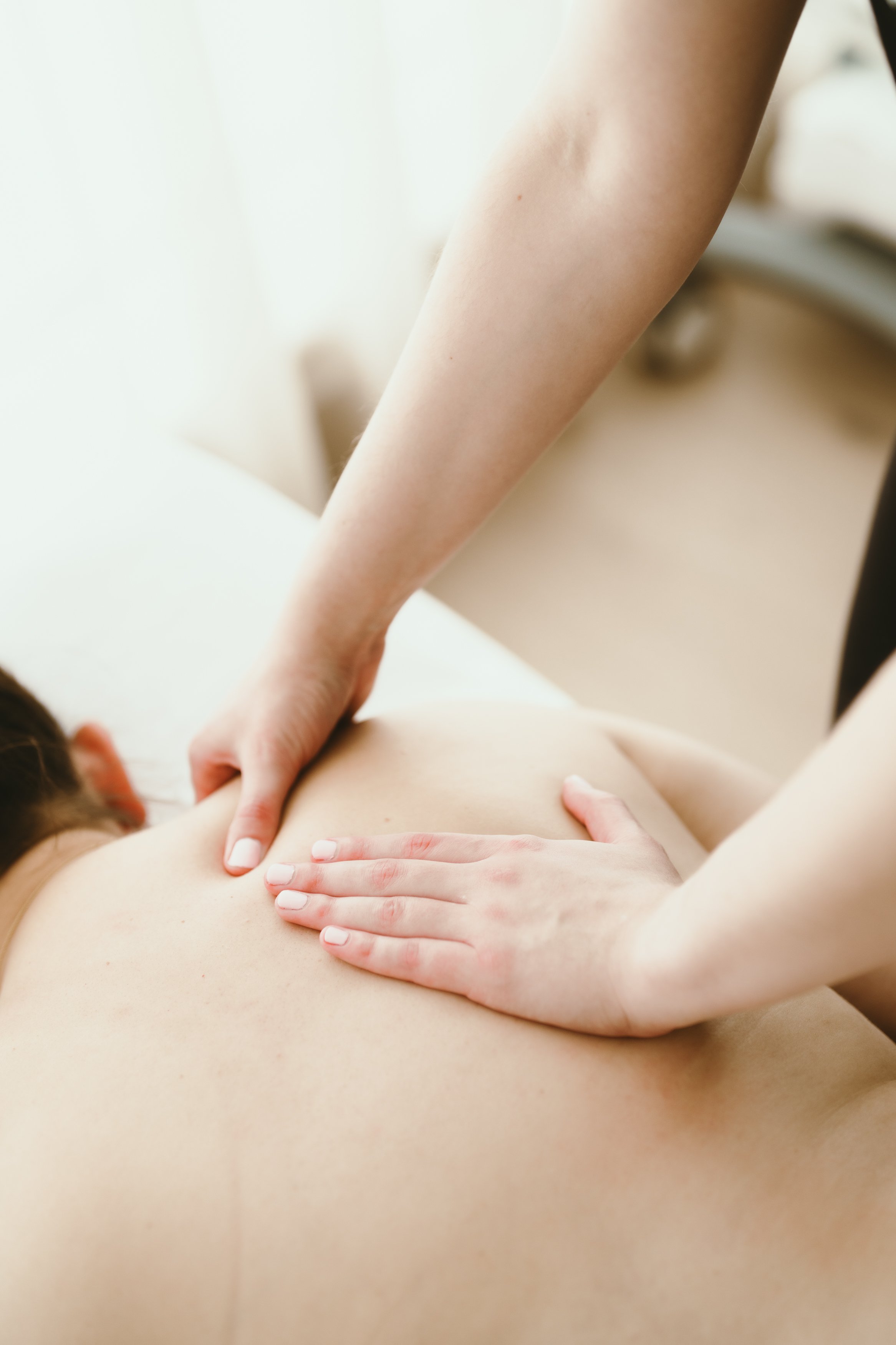 Person receiving a back massage from a massage therapist in a spa or clinic setting.