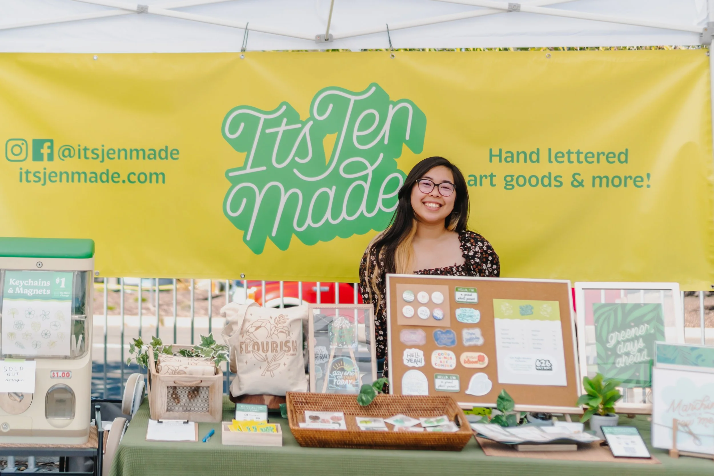 Jen smiling behind her booth at a craft market