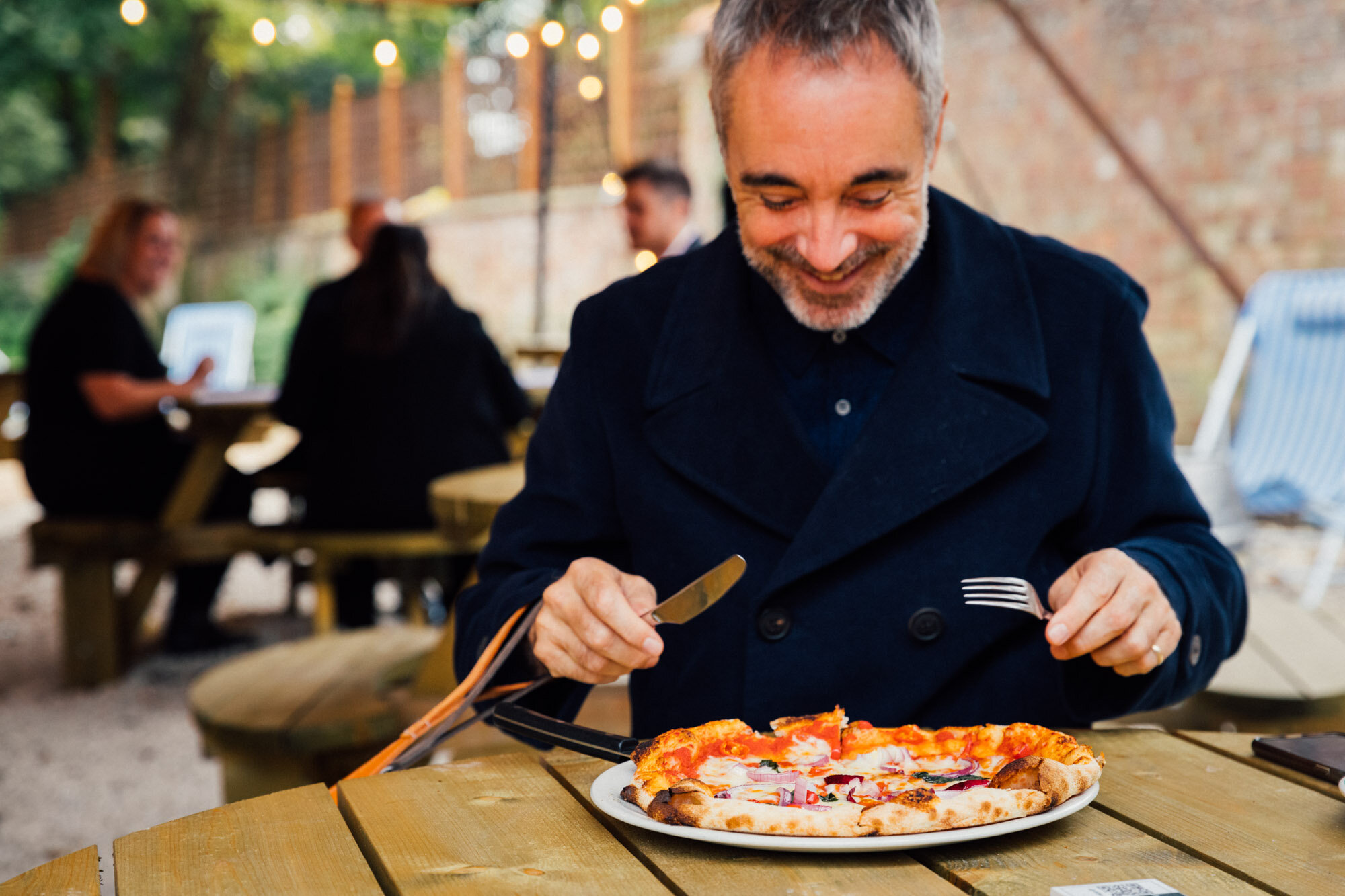 Customer eating wood-fired pizza from The White Hart in Ampthill.jpg