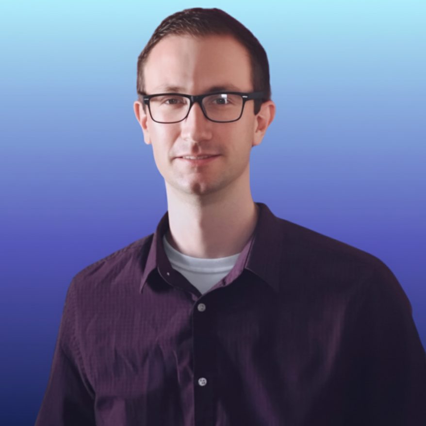 A young man with glasses and short dark hair, wearing a purple button-up shirt and a white T-shirt underneath, standing against a blue gradient background.