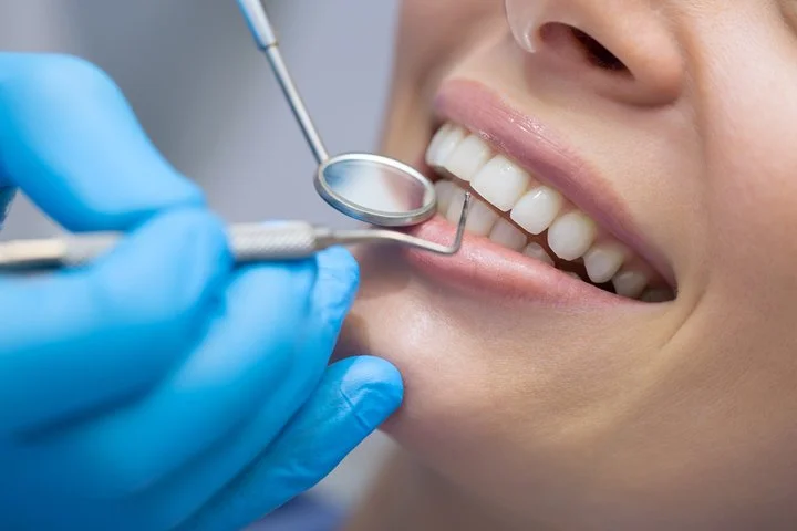 Close-up of a dentist examining a patient's teeth using dental mirror and probe