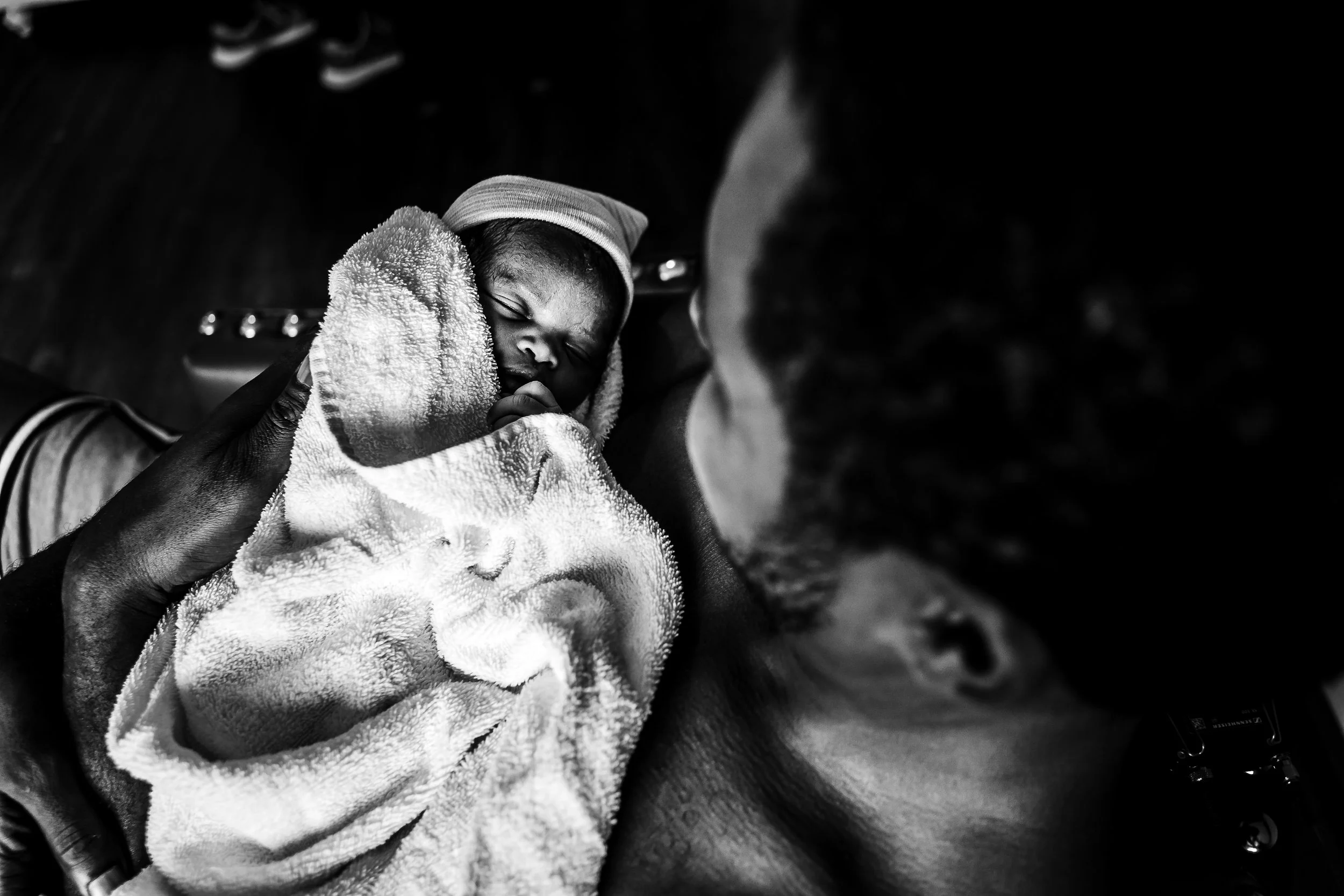 High key black and white photography, dad holding newborn baby wrapped in a towel after birth in Tulsa OK