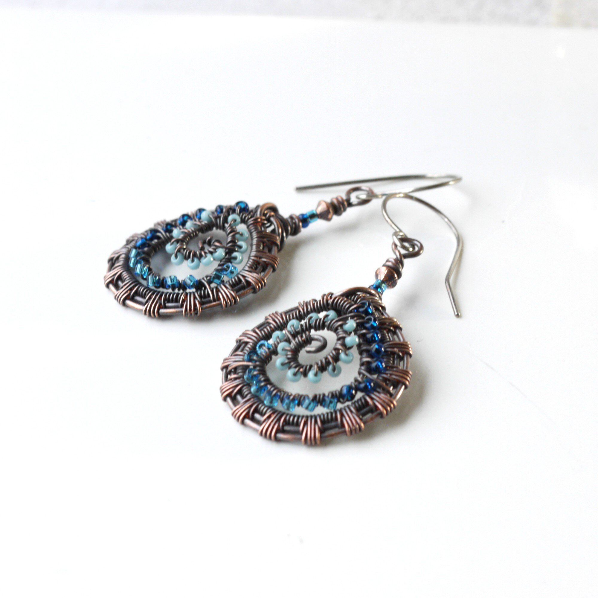 https://images.squarespace-cdn.com/content/v1/58ece8dff7e0ab189ab817d6/1594136368080-VX0WPNNPIW4WS5NAHYVV/6c-blue-bead-copper-wire-woven-fossil-earrings-sterling-silver-artisan-handmade-iris-elm-jewelry.jpg