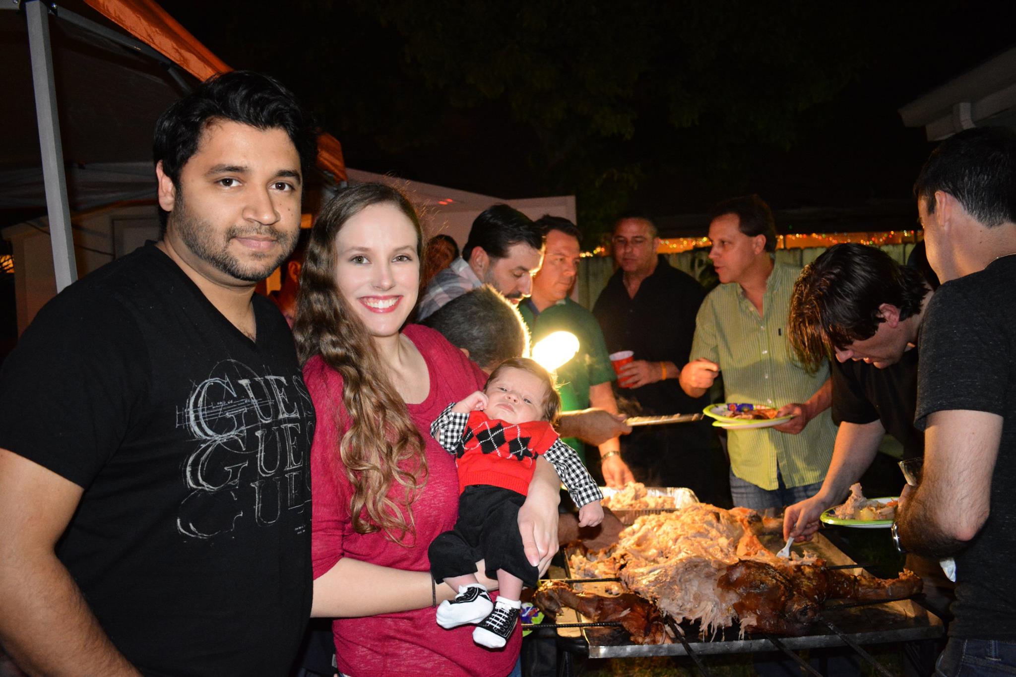 Noah at his first annual pig roast (almost 1 month old!), with Tio Ray carving el puerco in the background and Cousin Louie holding up the lamp.