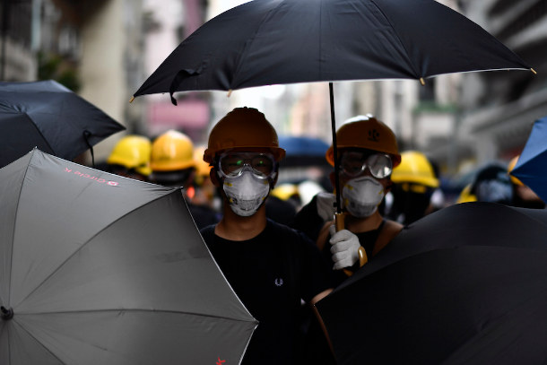Pro-democracy protesters stand together with umbrellas as they face off with police during a demonstration in Hong Kong on July 28. (Photo by Anthony Wallace/AFP)