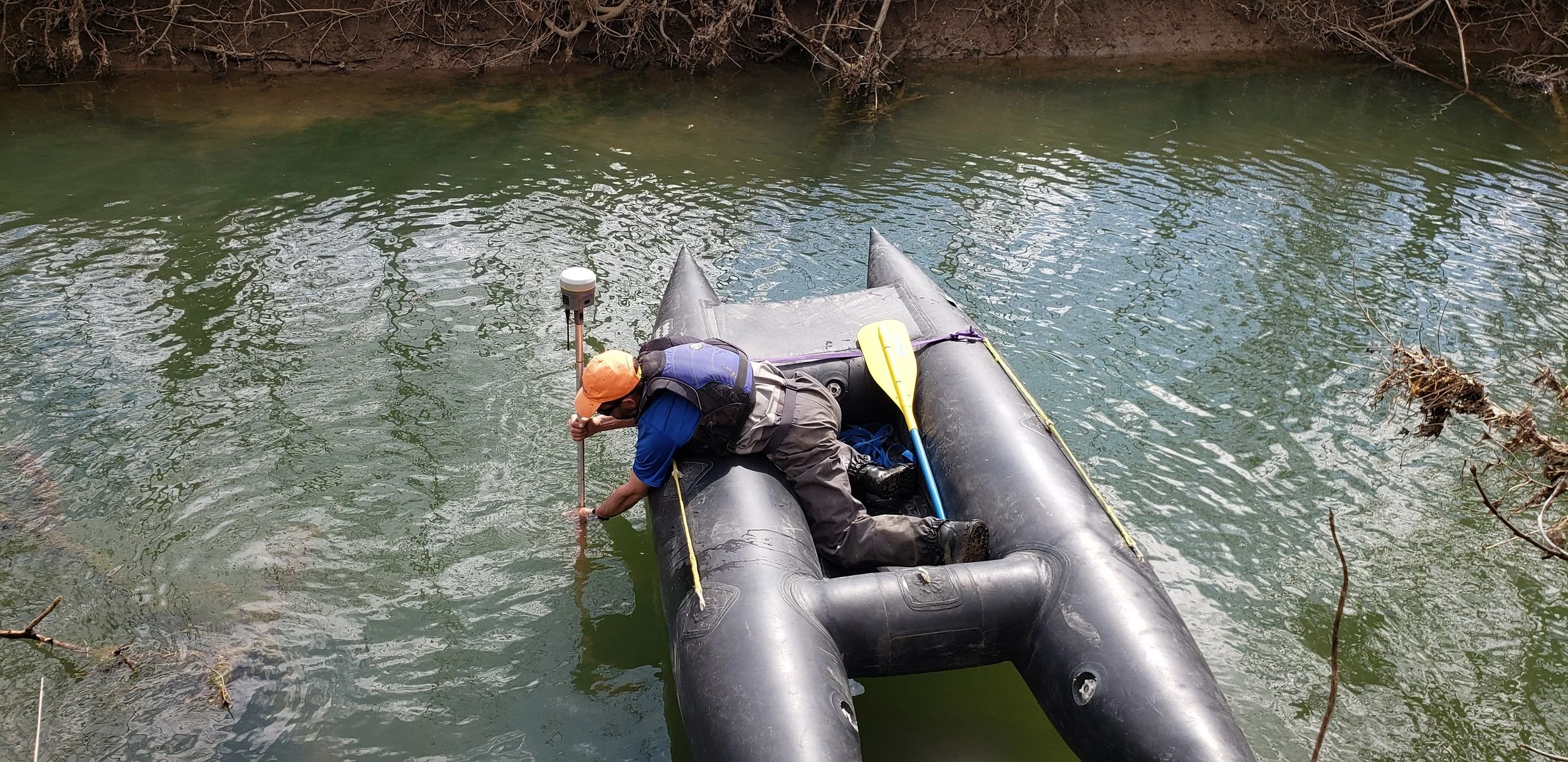 Surveyor on inflatable with GIS equipment on the stream.