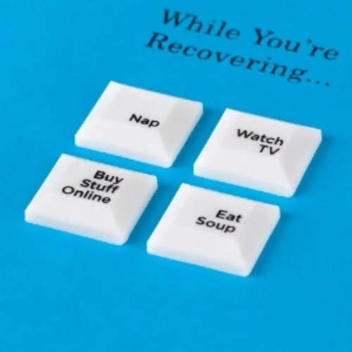 A close up of a bright blue greeting card that says "While you're recovering ... " at the top and includes four white buttons: nap; watch tv; buy stuff online, eat soup.