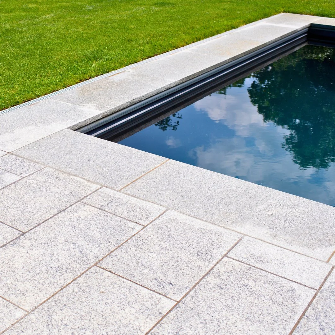 Even as the weather cools, we&rsquo;re dreaming of next summer. This elegant Guilford Grey granite patio blends natural stone with lush greens, creating the perfect balance of structure and serenity.