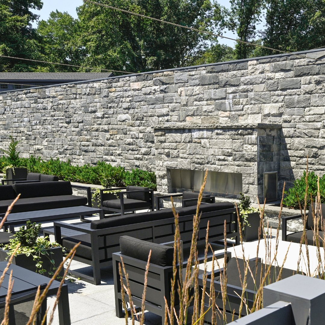 Gather with friends and unwind fireside on this stunning granite patio, featuring a Salem Dark Granite veneer, fireplace, and ample seating for every season. See this space come to life at The Mill in Westport.