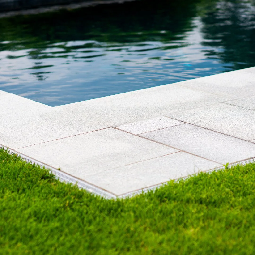 Clean lines. Natural balance. This Guilford Grey pool patio&rsquo;s precise edge creates a seamless transition between stone and landscape.